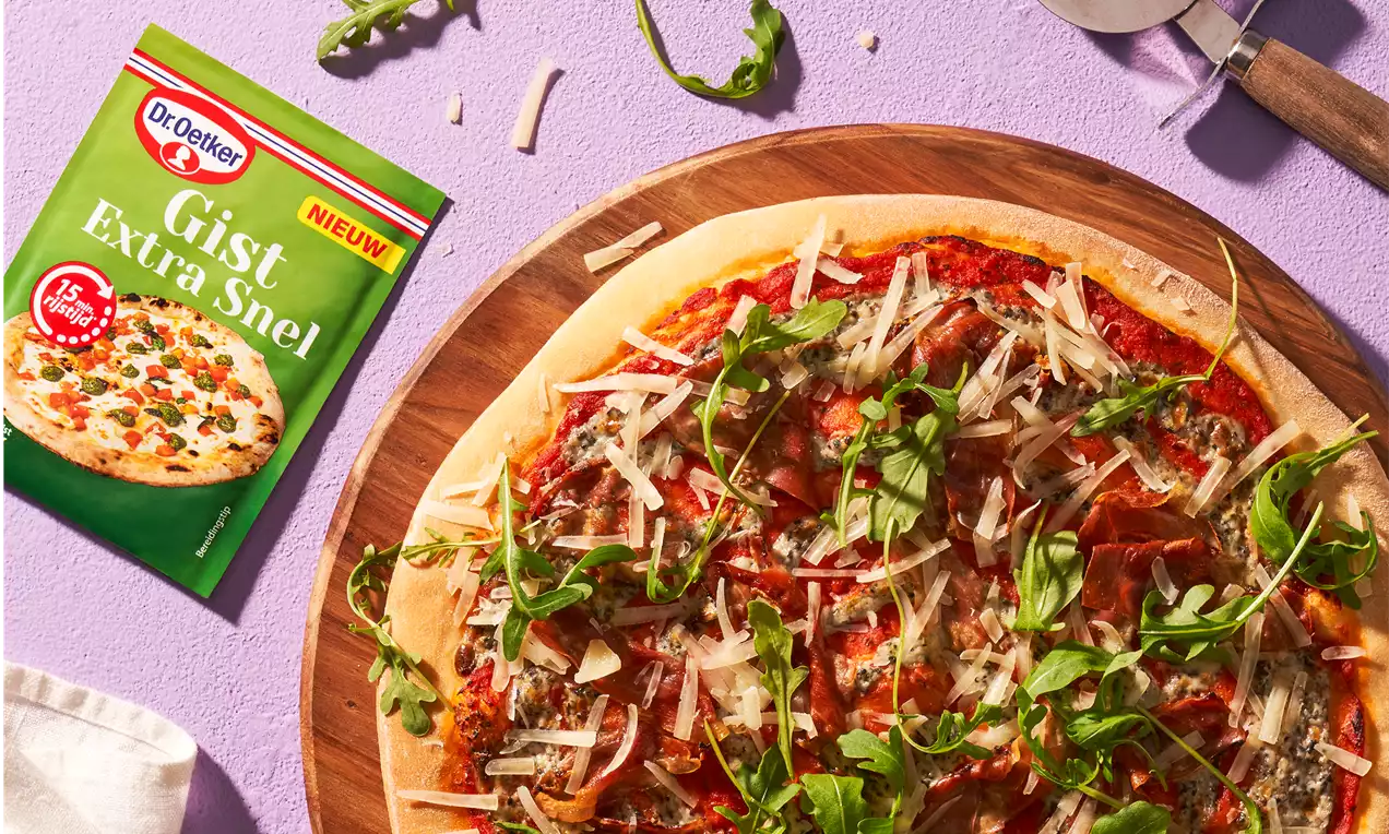 Ronde pizza op een houten plank met rode tomatensaus, gesmolten kaas, groene rucola, geraspte kaas en een paar losse blaadjes ernaast